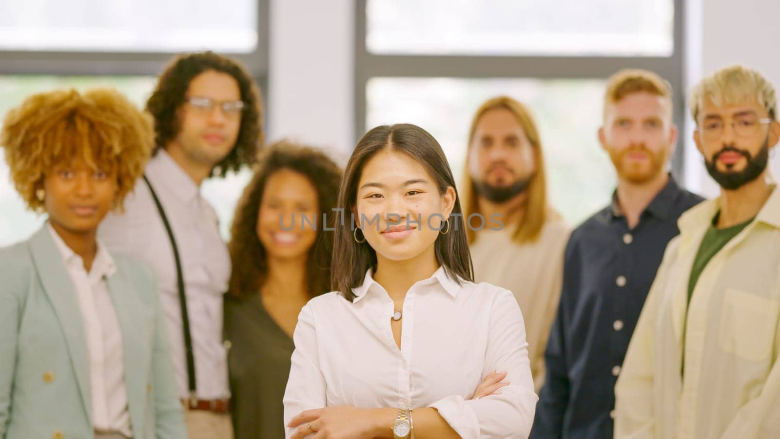 Chinese woman leading a work team in the office standing proud and looking at camera together