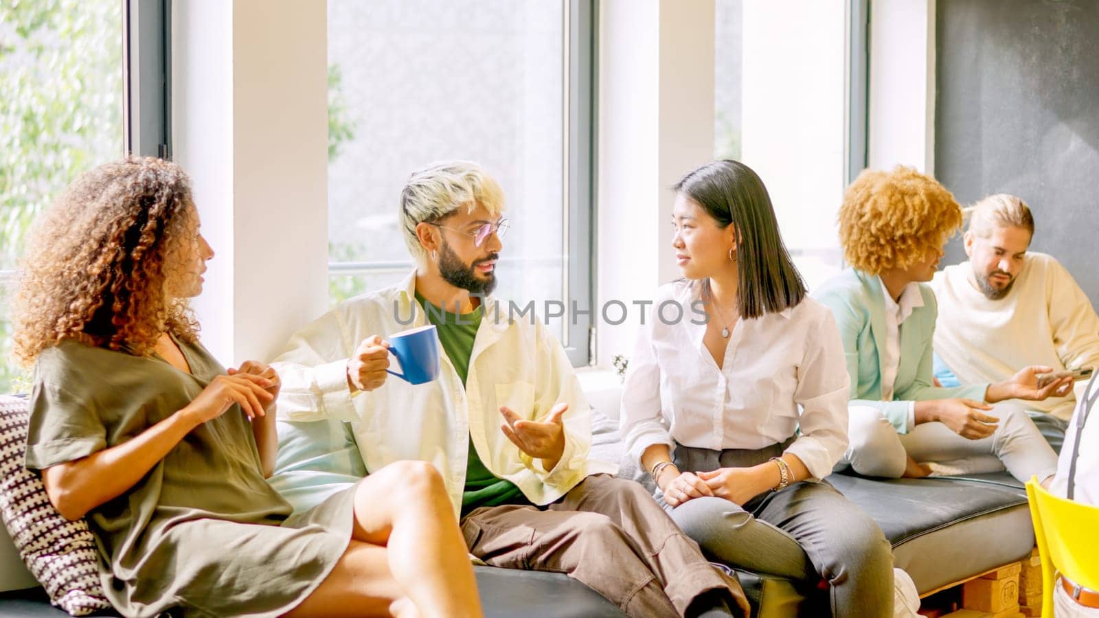 Coworkers chatting relaxed during coffee break sitting on comfortable chairs
