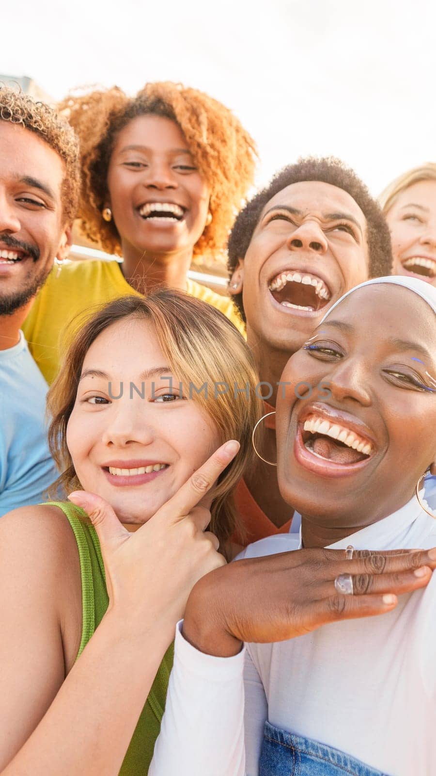 Excited multiethnic friends taking selfie outdoors during sunset by ivanmoreno