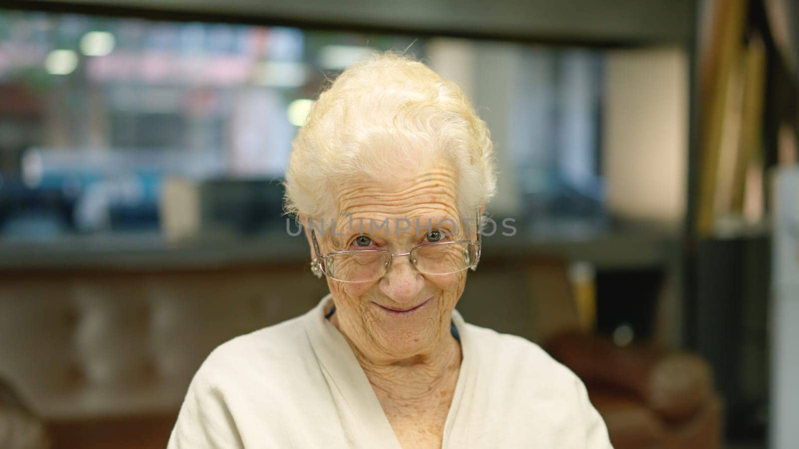 Old woman smiling at camera sitting in a nursing home by ivanmoreno