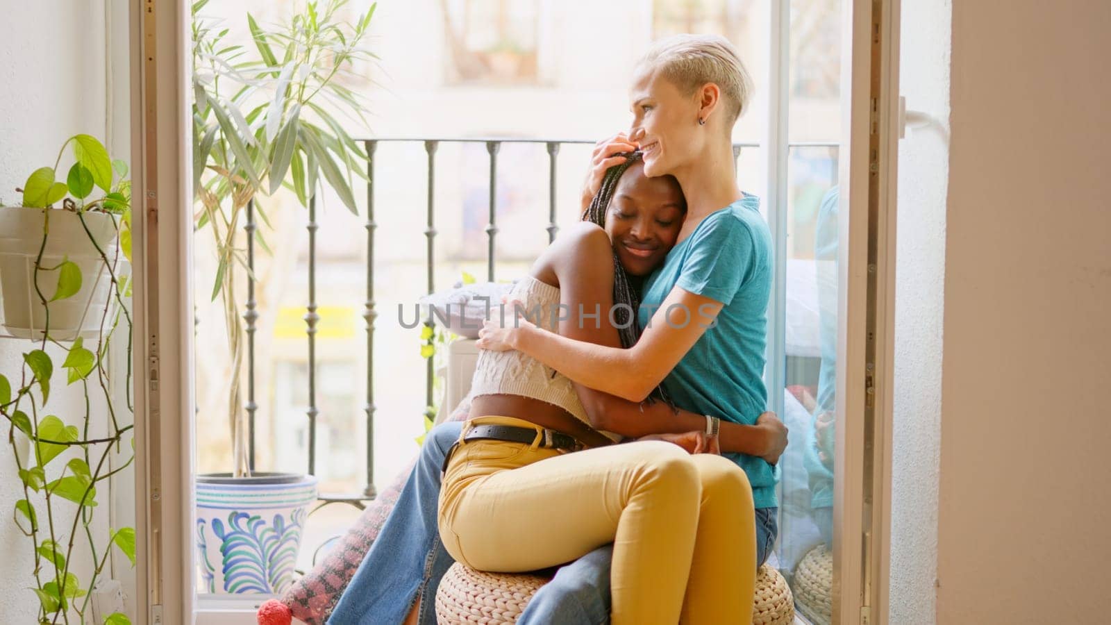Lesbian lovers embracing sitting on the balcony at home