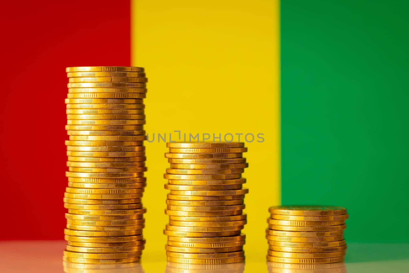 Three golden coin stacks from highest to lowest against flag of Republic of Guinea by VitaliiPetrushenko