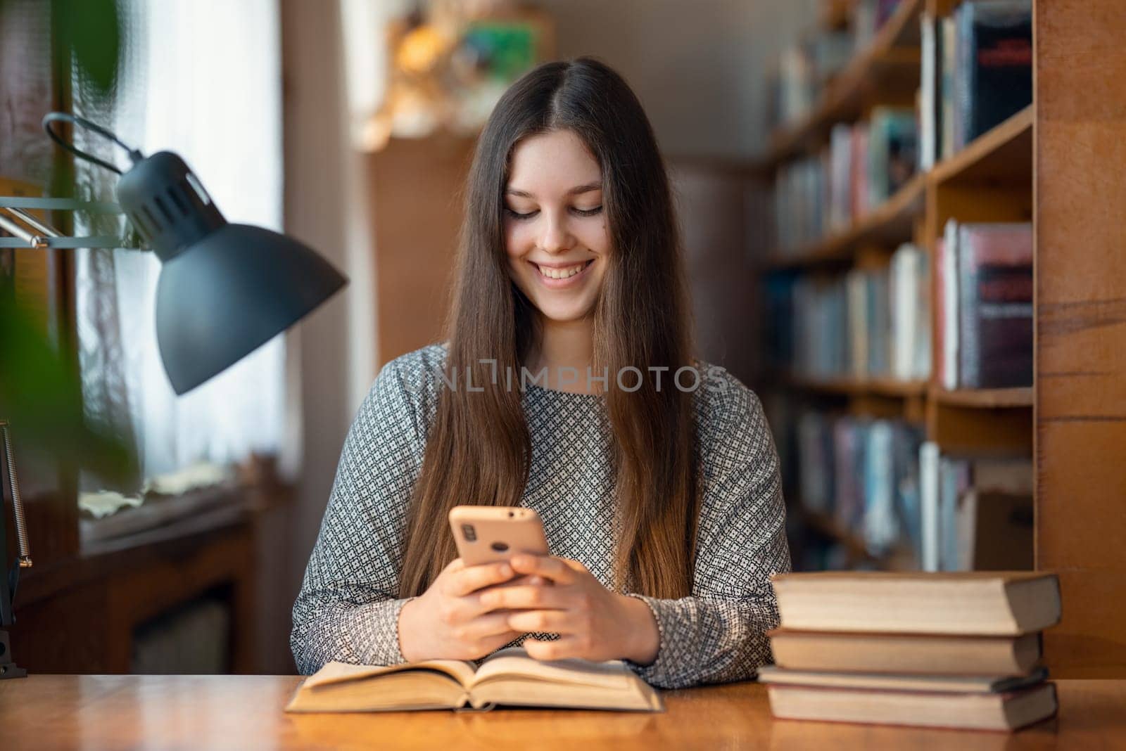 Happy smiling university student girl using her mobile phone by VitaliiPetrushenko