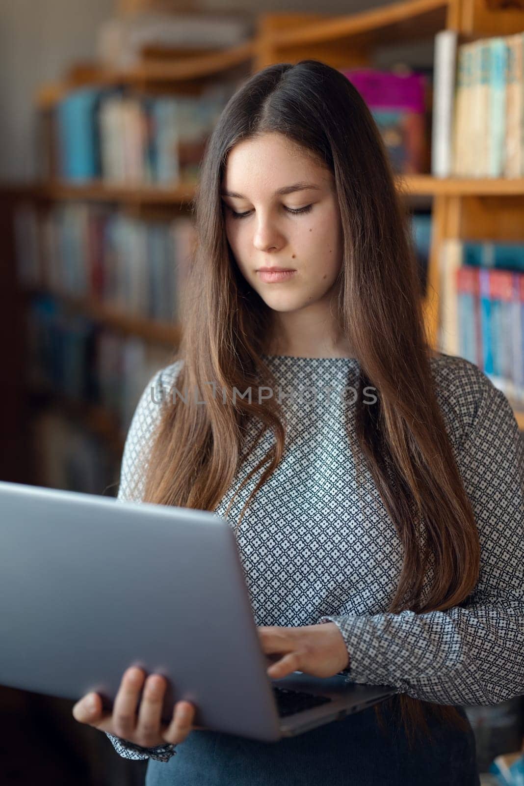 Female learner studying in library, using modern computer, study class assignment