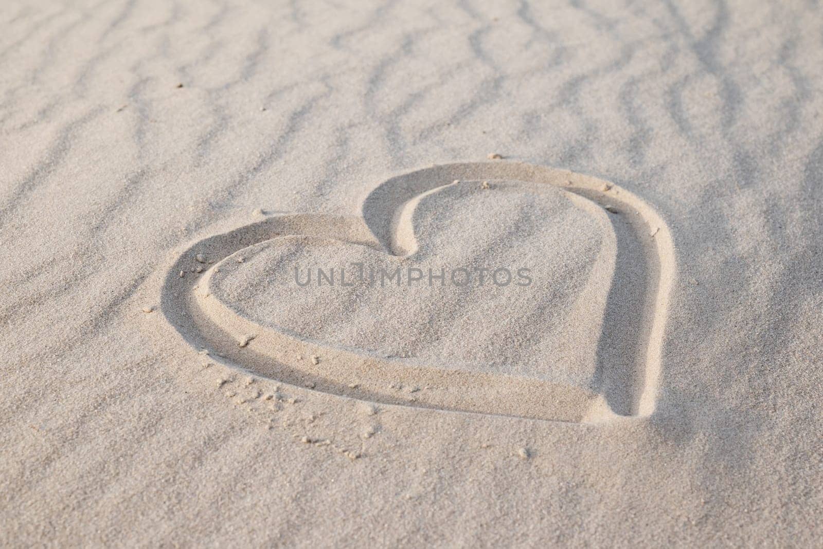 Heart drawn in sand beach, evening warm light by VitaliiPetrushenko