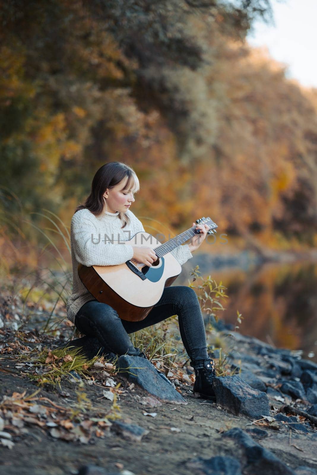 Portrait of a young girl playing the guitar near river by VitaliiPetrushenko