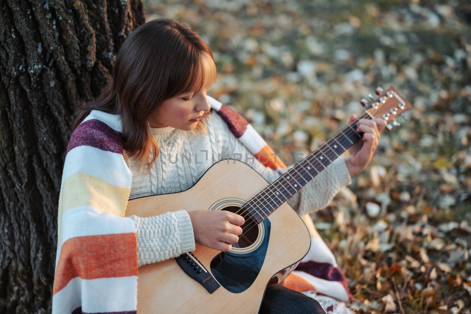 Beautiful evening shot of a girl musician outdoors in autumn nature