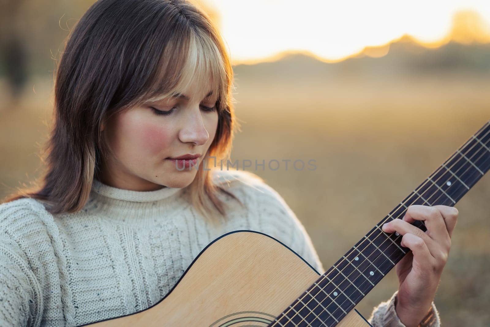 Young girl play the guitar outdoor in autumn park