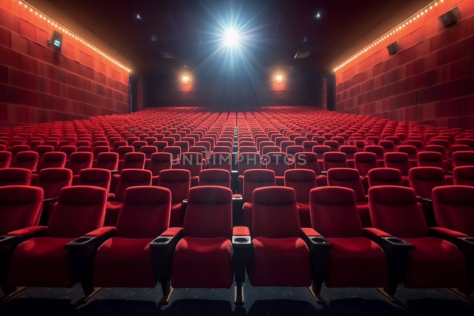 Empty cinema hall with red seats and screen illuminated.