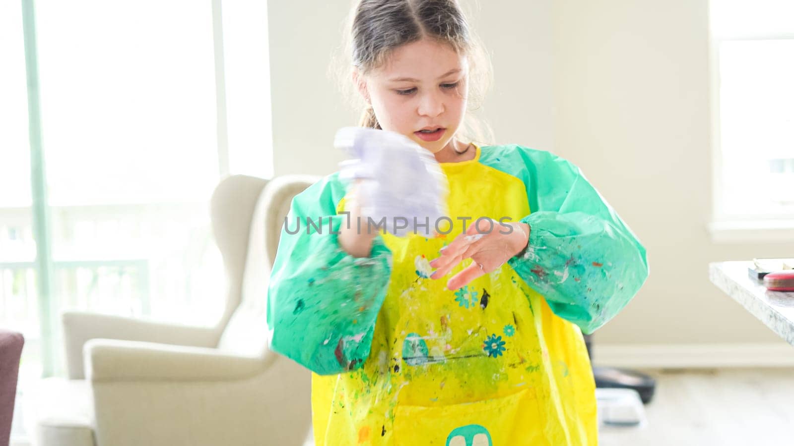 In a modern kitchen, a homeschooled girl is engrossed in creating homemade slime, a fun and educational hands-on project that enhances her creativity and problem-solving skills.