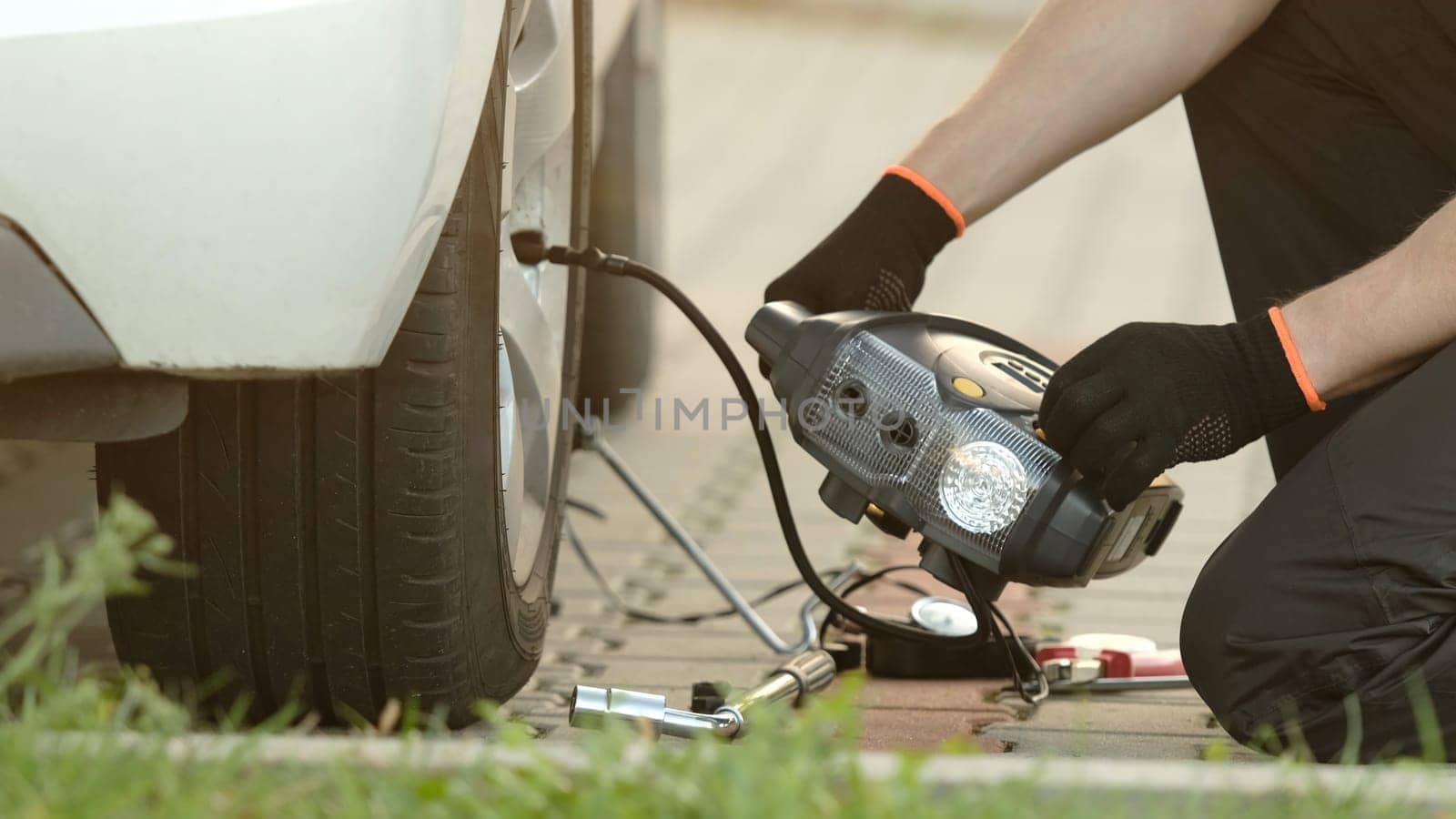 Man Inflates Tire With Portable Pump As Mechanic