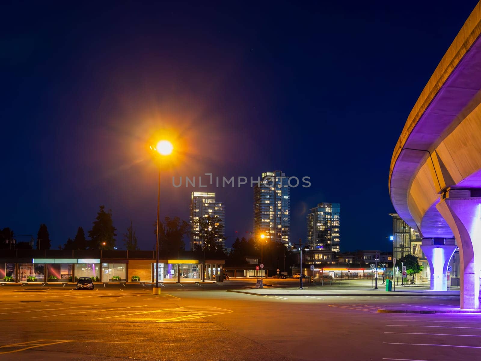 Night cityscape with skytrain line and bright street light over the plaza