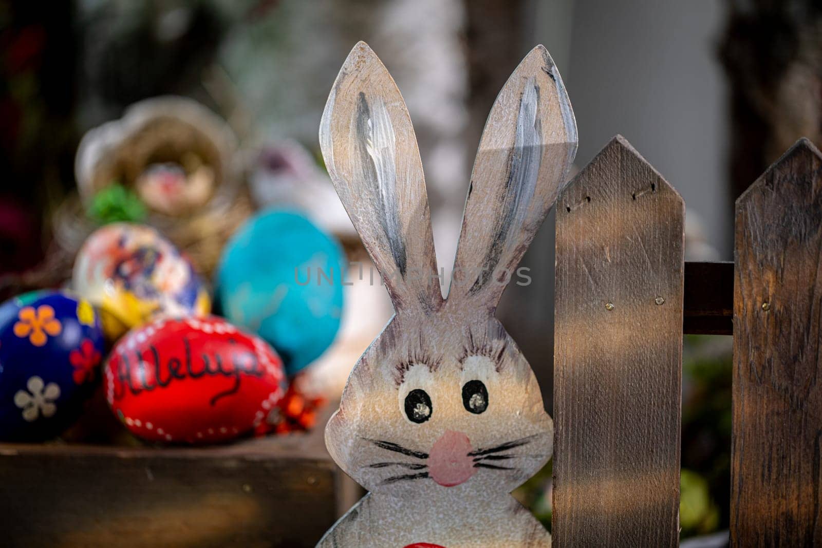 Positioned nearby, partially obscured by a gentle blur, are Easter eggs, with one standout egg in striking red bearing the word 'alleluia' in dark lettering.