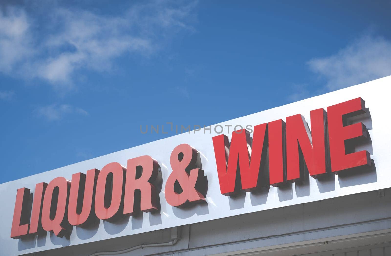 A Sign For A Liquor And Wine Store Against A Bright Blue Sky