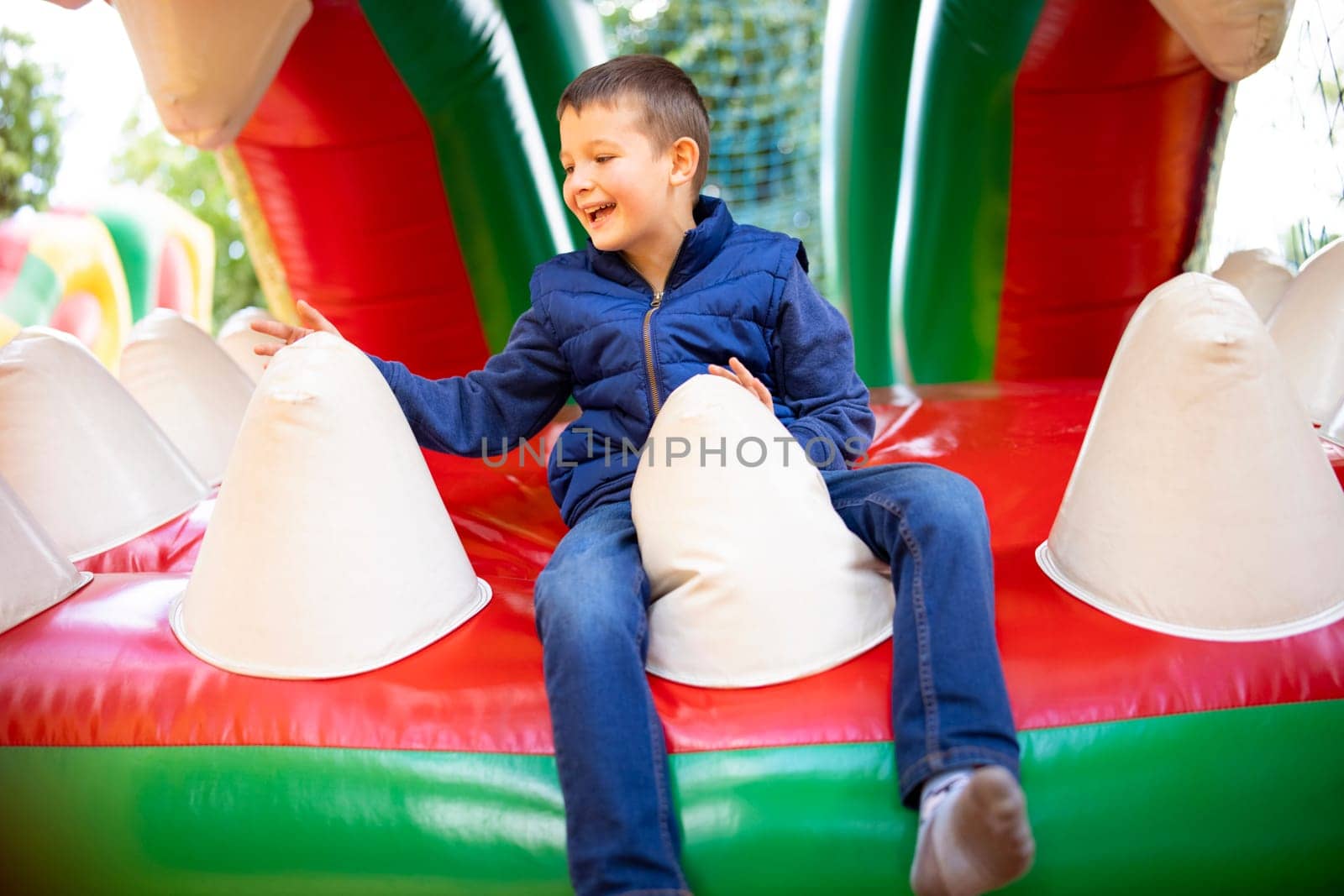Joyful boy playing on a colorful inflatable bouncy castle