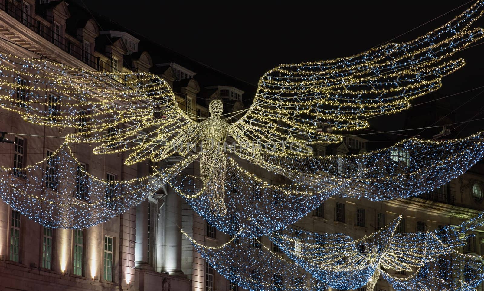 London, UK - Dec 25, 2023 - Flying angel Christmas decoration led lights display. Dramatic view of the traditional Christmas decoration lights hanging above Regent Street during dusk, The Spirit of Christmas, Light Festival in London, Space for text, Selective focus.
