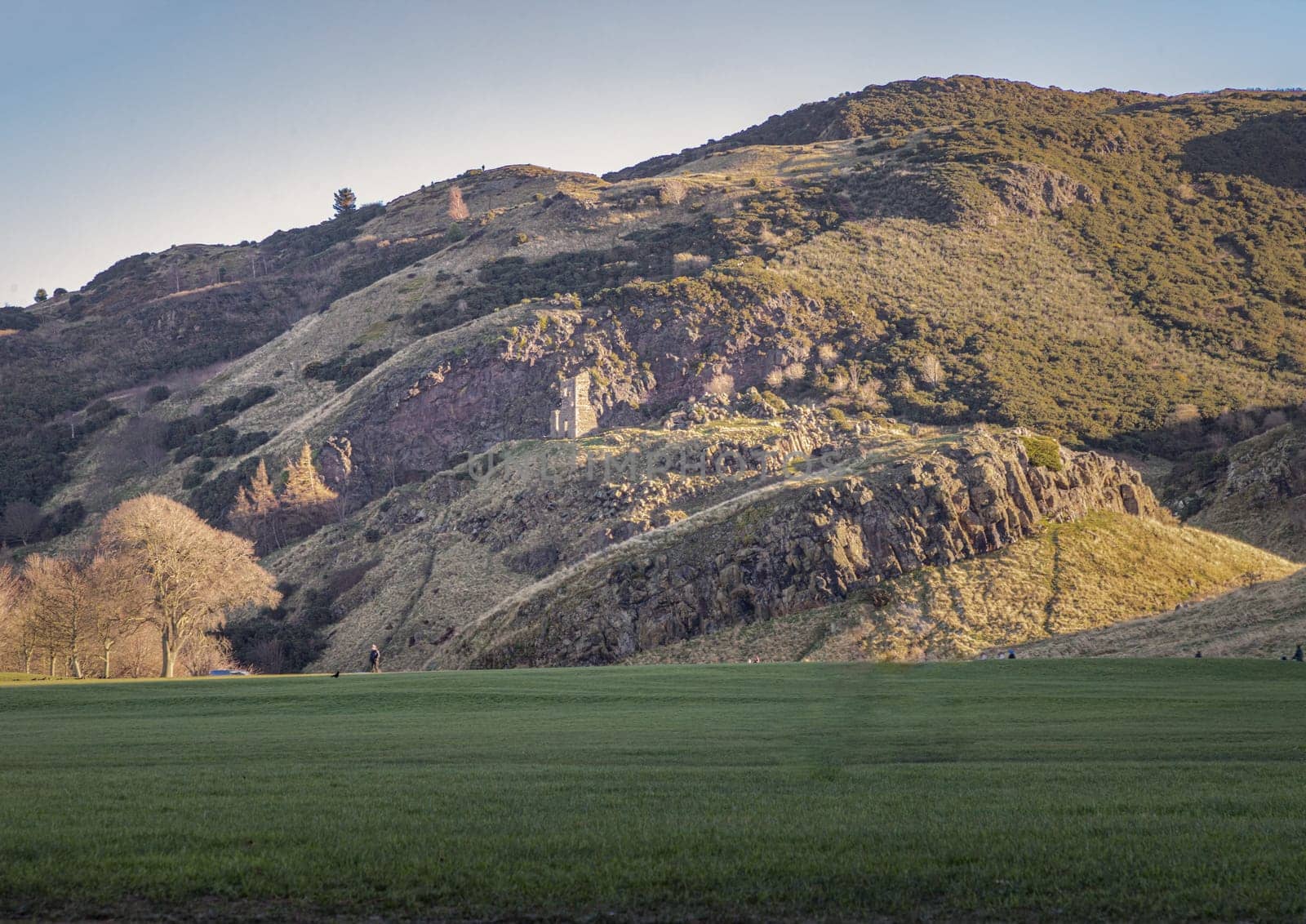 The breathtaking scenic landscape of Holyrood park with Salisbury Crags rugged hills and sky background. View of Edinburgh city. Space for text, Selective focus.