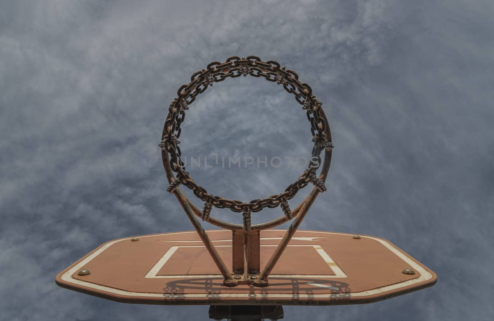 Edinburgh, Scotland, Jan 19, 2024 - View of Basketball backboard with the hoop metal ring and steel chain net against blue sky background seen from below. Street basketball court, Low angle view, Look up, Space for text, Selective focus.