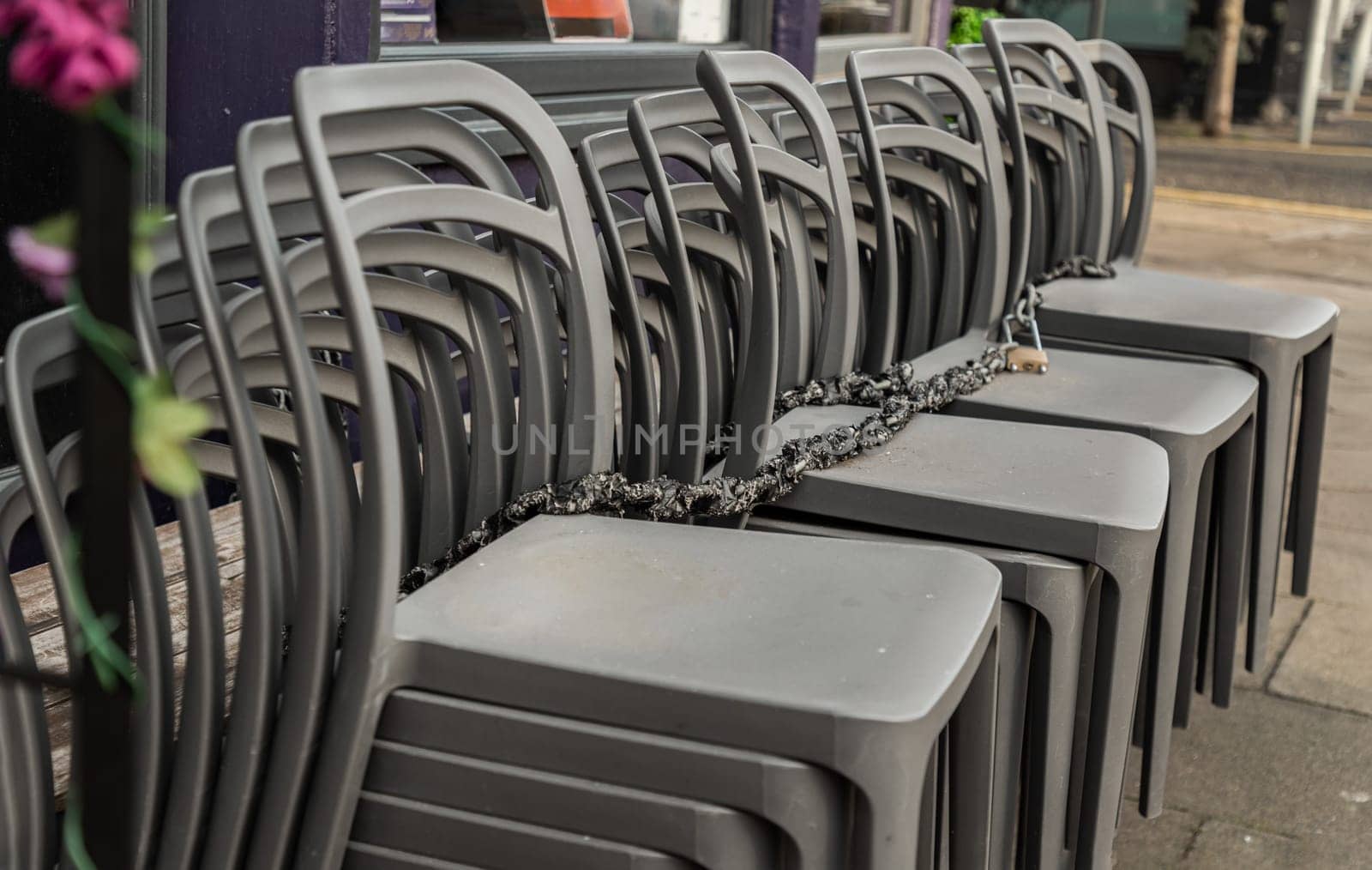 Pile of stacking silver gray plastic chairs are beside of The cafe terrace at sunny day. Detailed of pattern stack plastic chairs, Space for text, Selective focus.