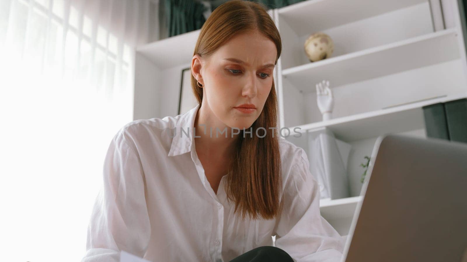 Young businesswoman sitting on the crouch using laptop computer for prim work by biancoblue