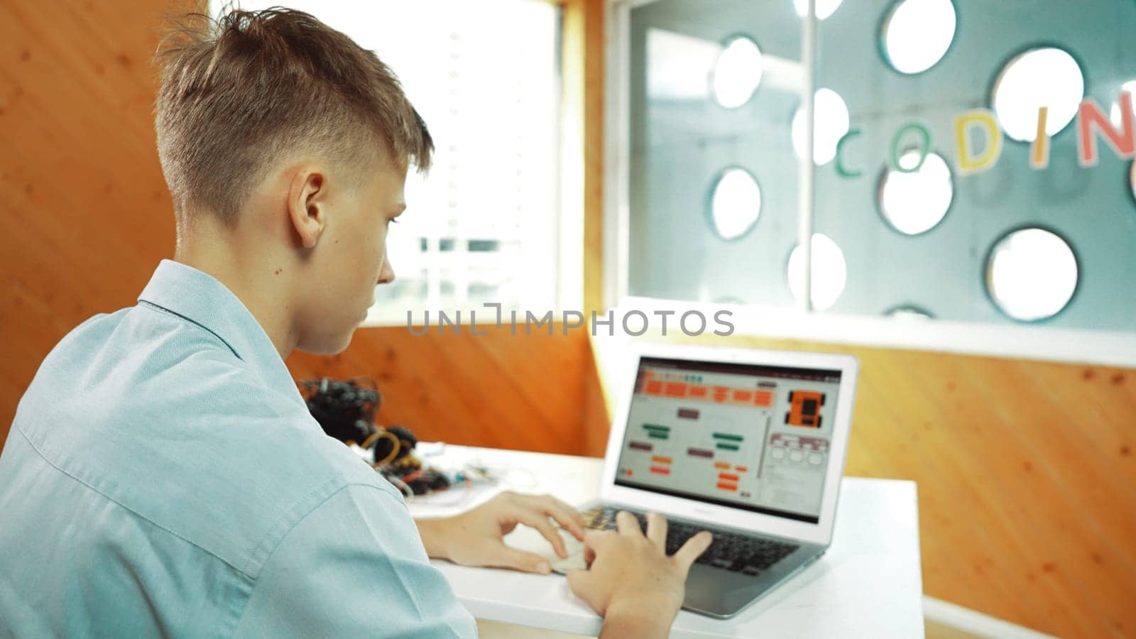 Back view of highschool student working on laptop analysis data at STEM science class. Smart happy caucasian boy learning to coding engineering prompt or programing system at STEM class. Edification.