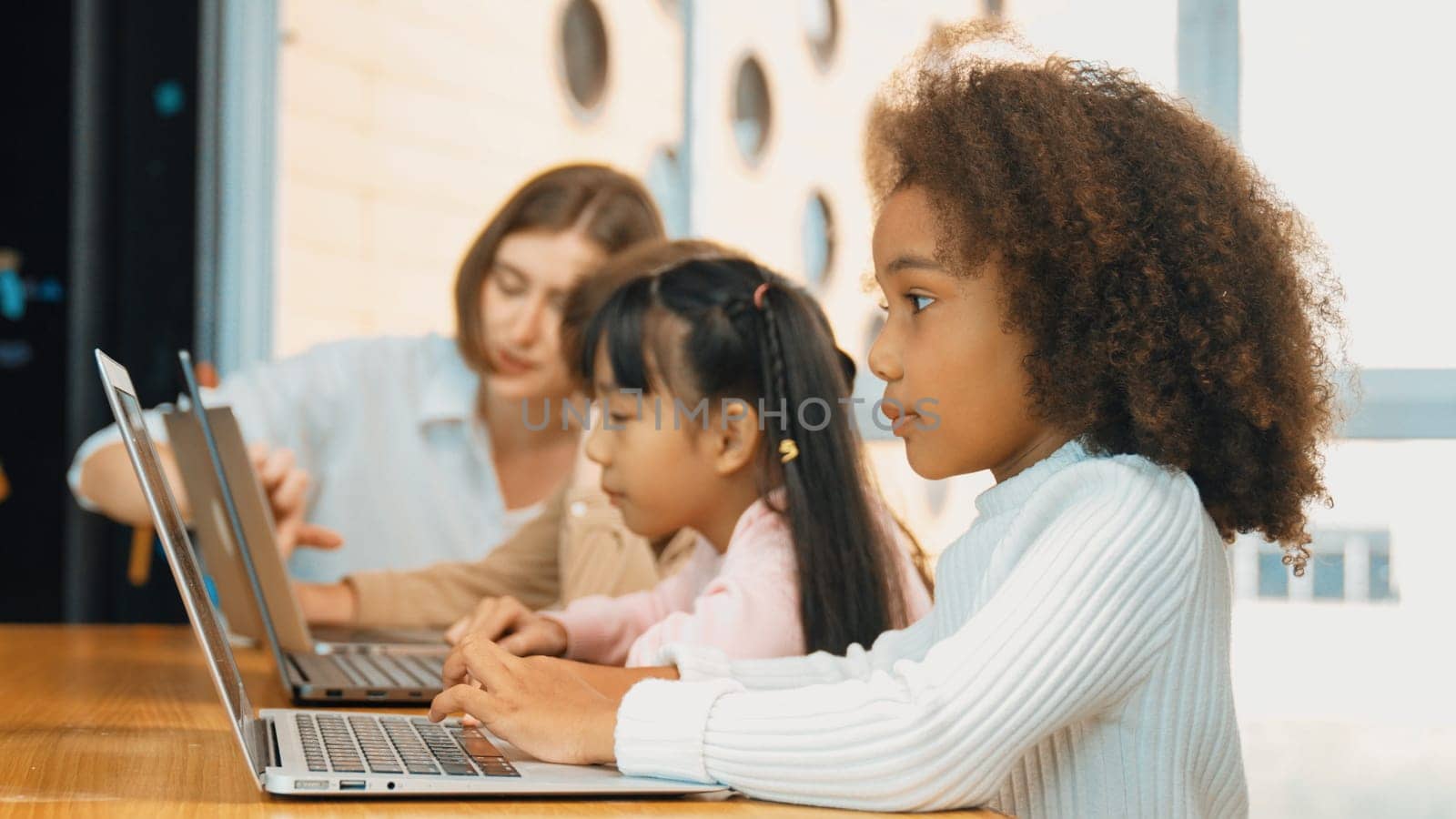 African girl play laptop with diverse friend learning prompt at STEM technology class. Multicultural student study about engineering code and programing system with blurring background. Erudition.