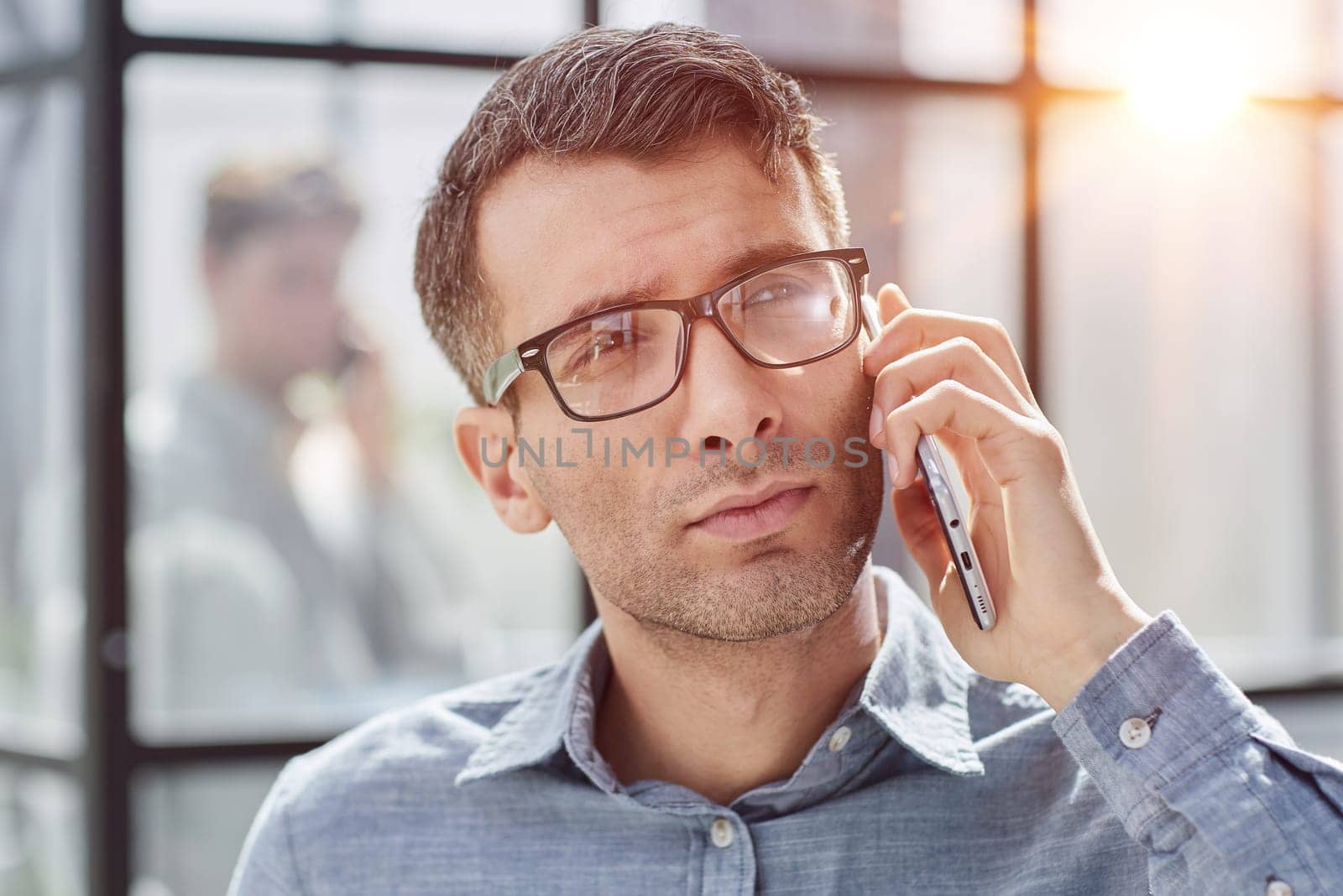 young man in a blue shirt talking on the phone in the office