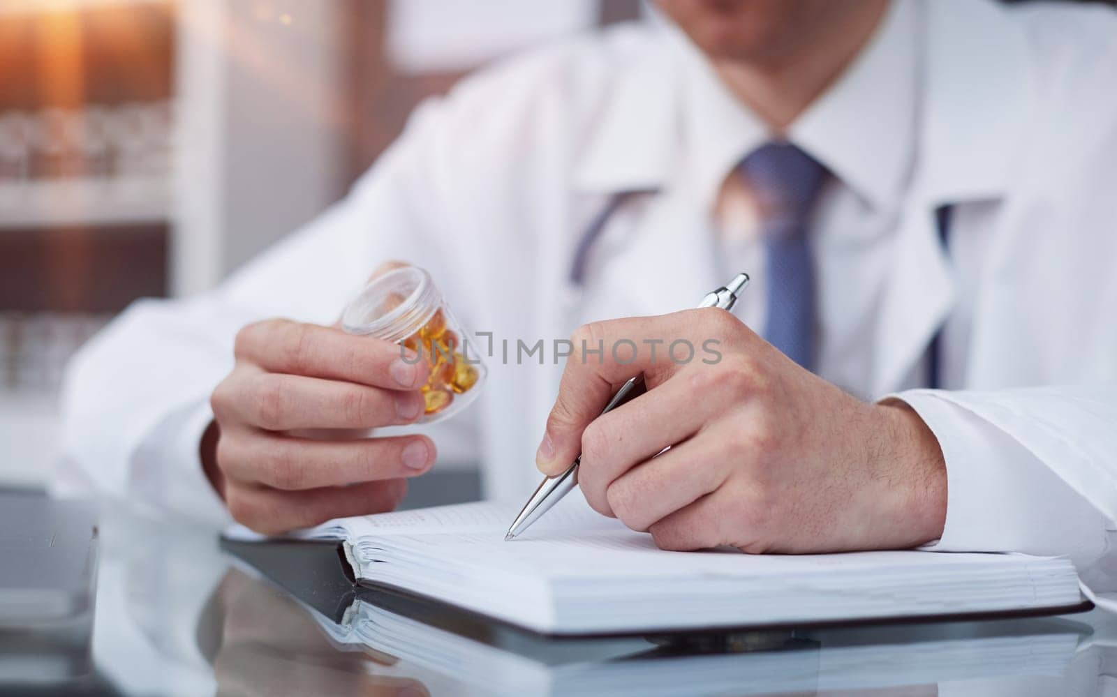 doctor holding pills and making notes in a notebook by Prosto