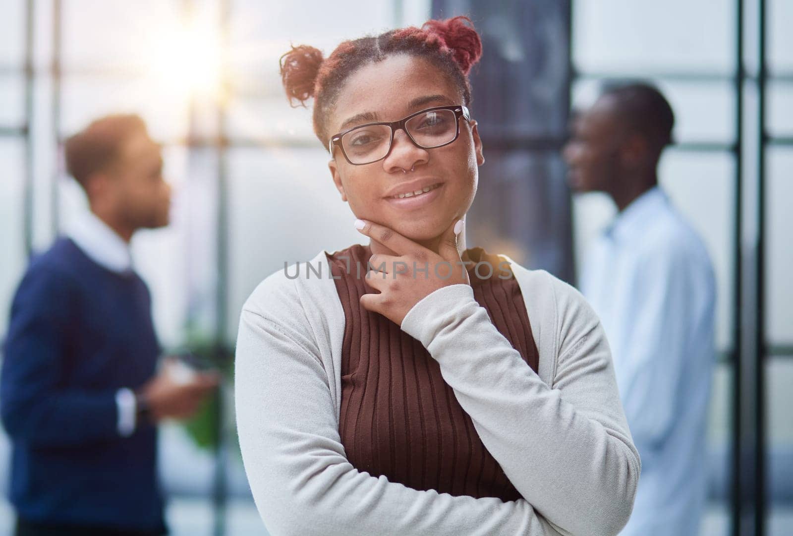 She is standing in a modern office with her colleagues in the background. by Prosto