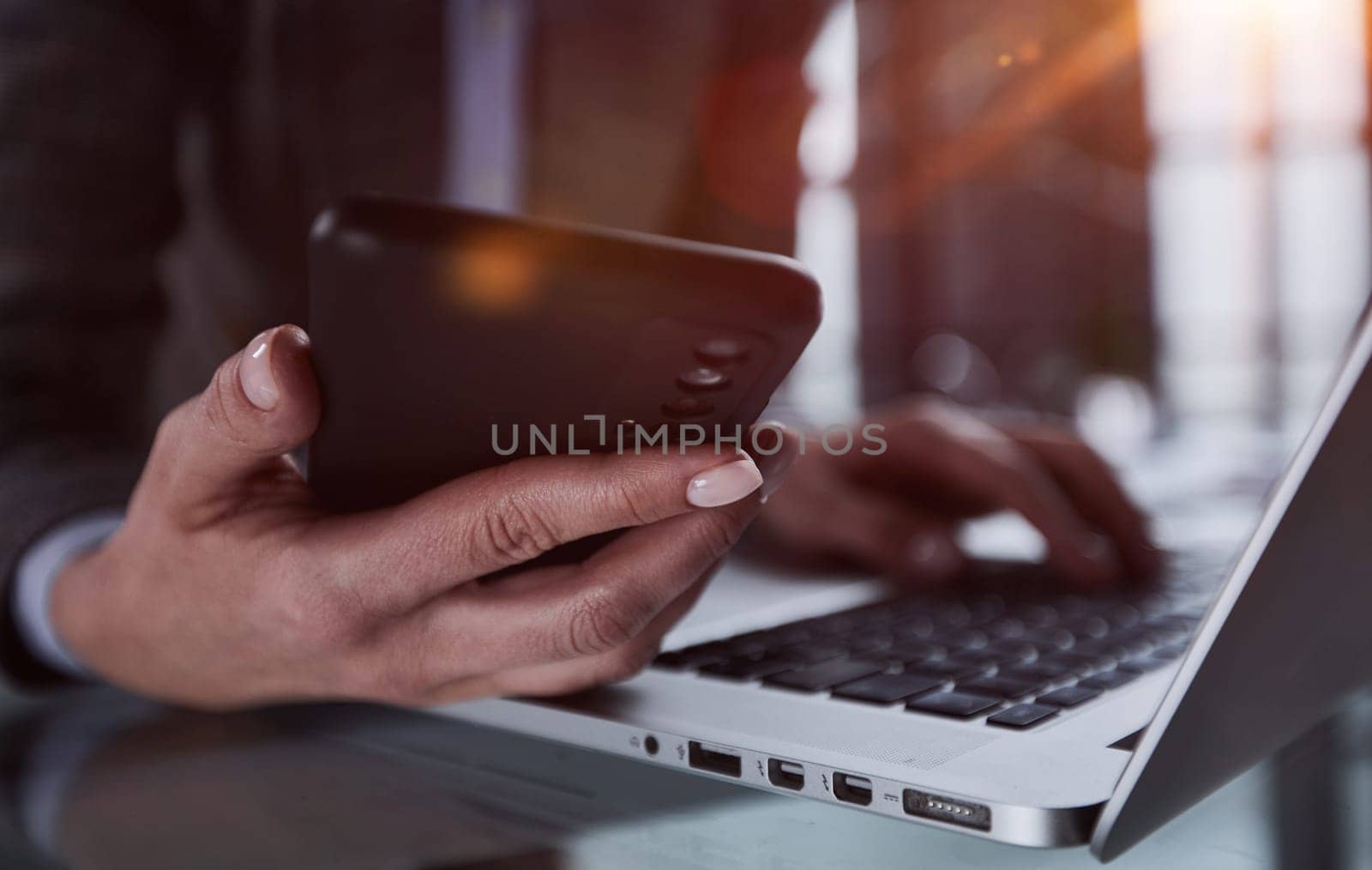 male hands hold a smartphone and use it for online shopping while looking at a laptop