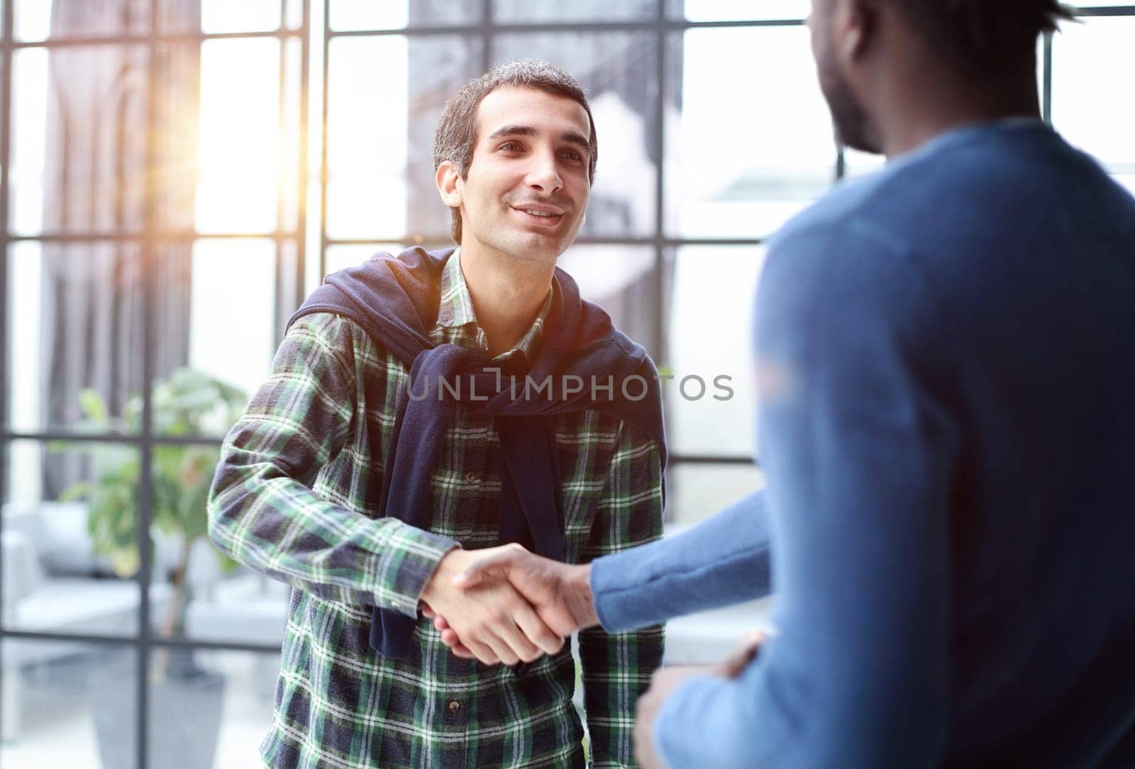 Diverse male colleagues in modern office corridor, young african american and caucasian business people discussing common project work, meeting in company work