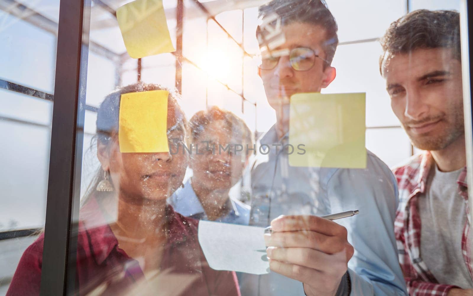 A group of business people behind a glass wall in the office sticking notes by Prosto