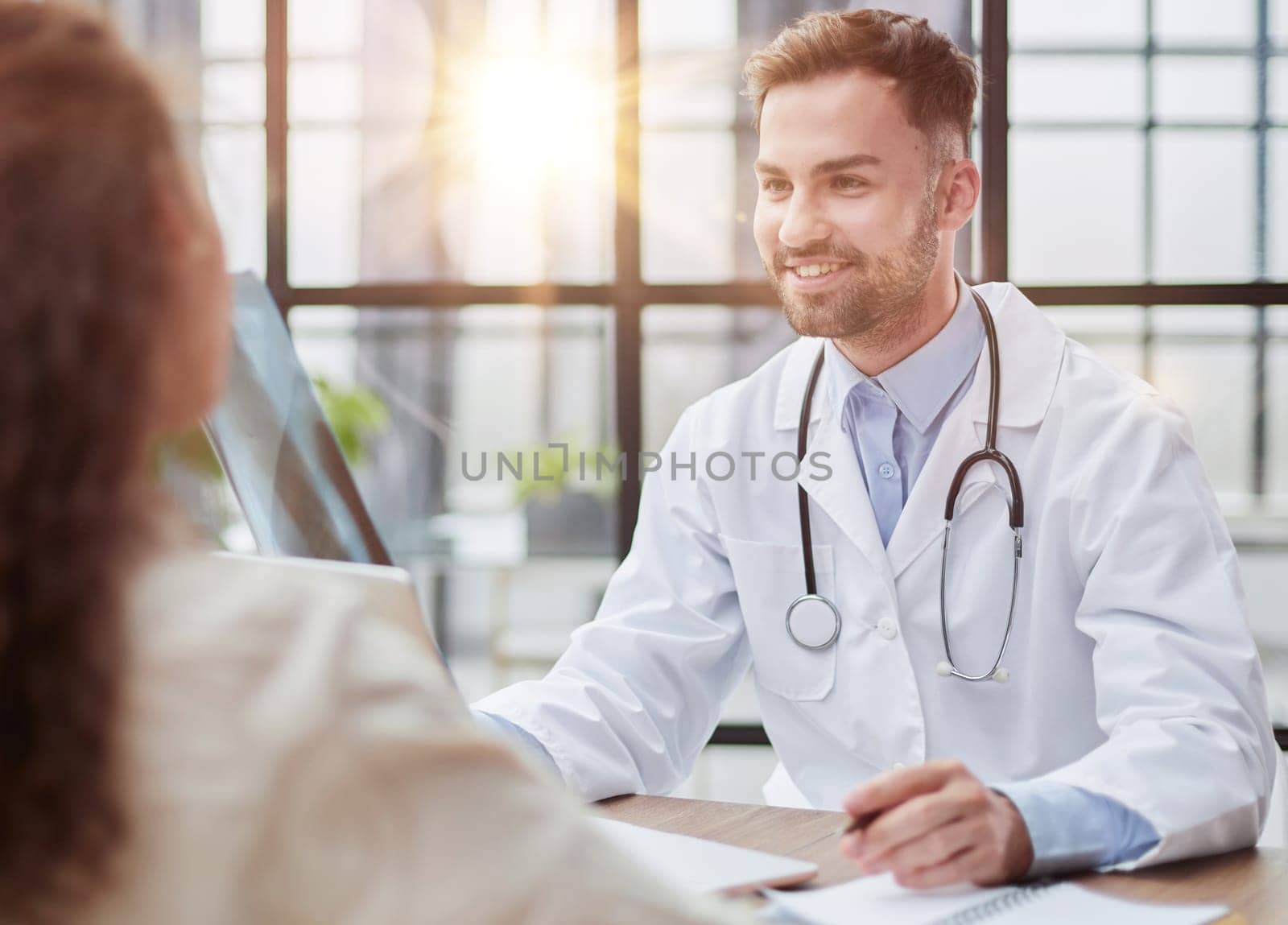 Young serious competent male doctor looking at X-ray at doctor's office