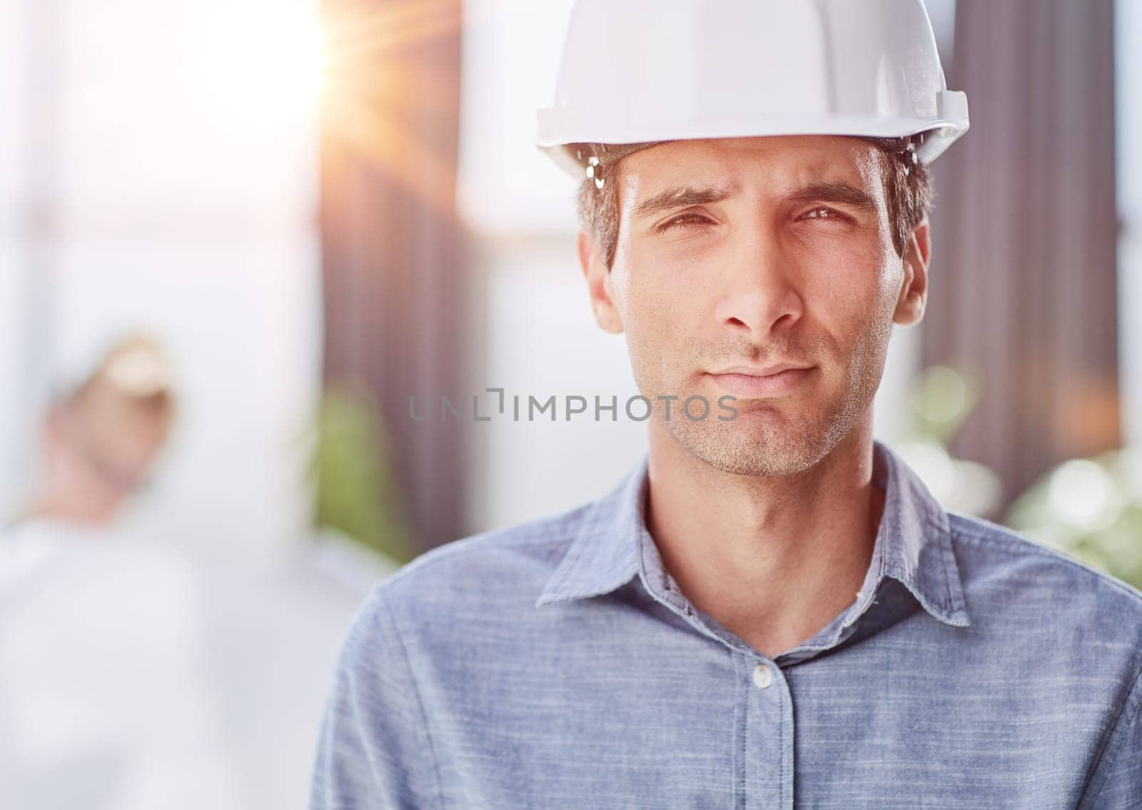 Smiling young unshaven business man in light shirt protective construction helmet.