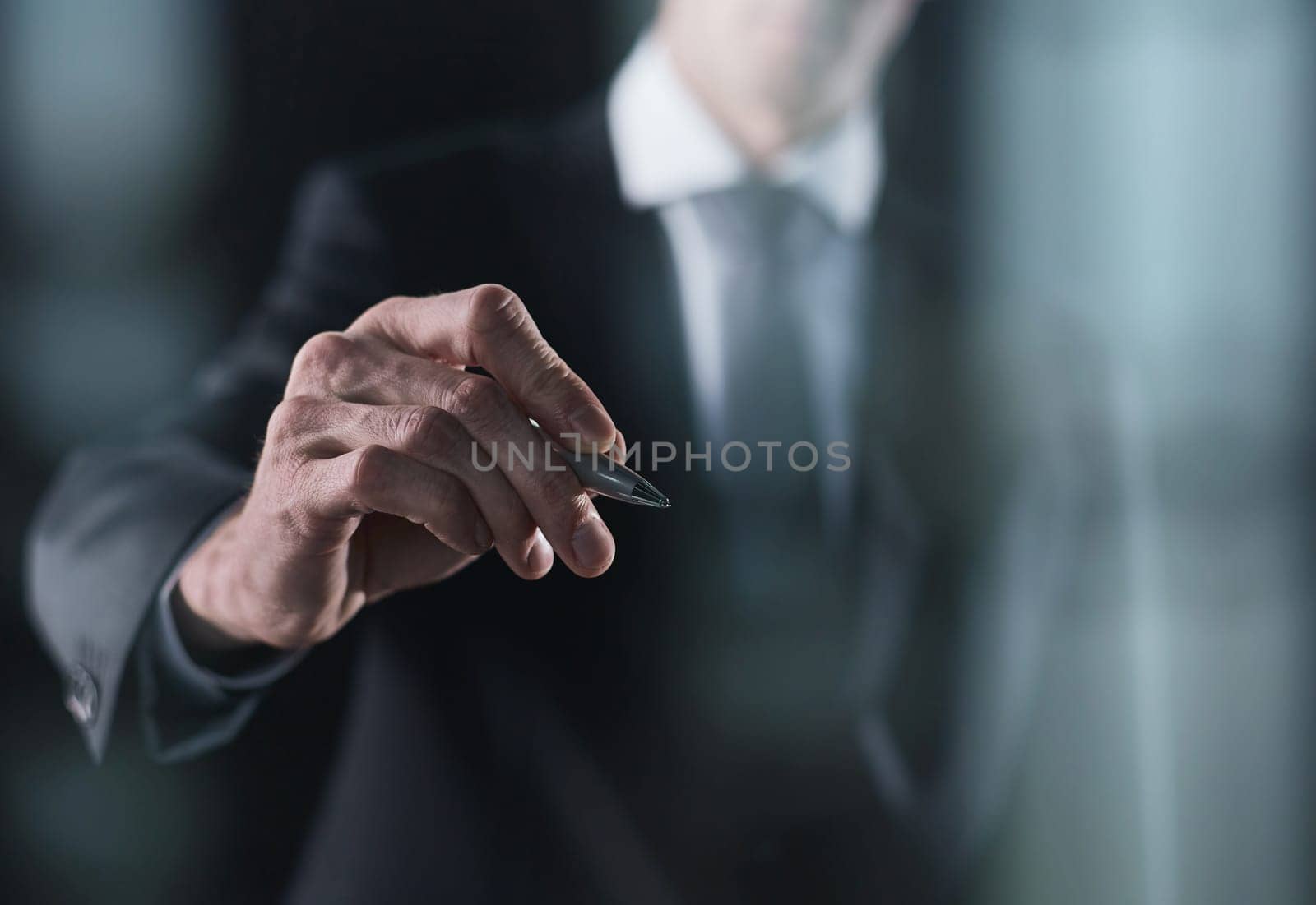 A hand holding a marker turned to the camera against a dark background