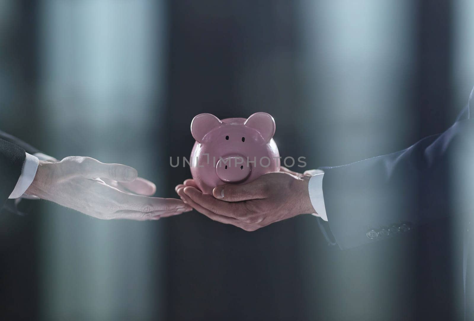 A businessman gives you a piggy bank isolated on a black background. banking