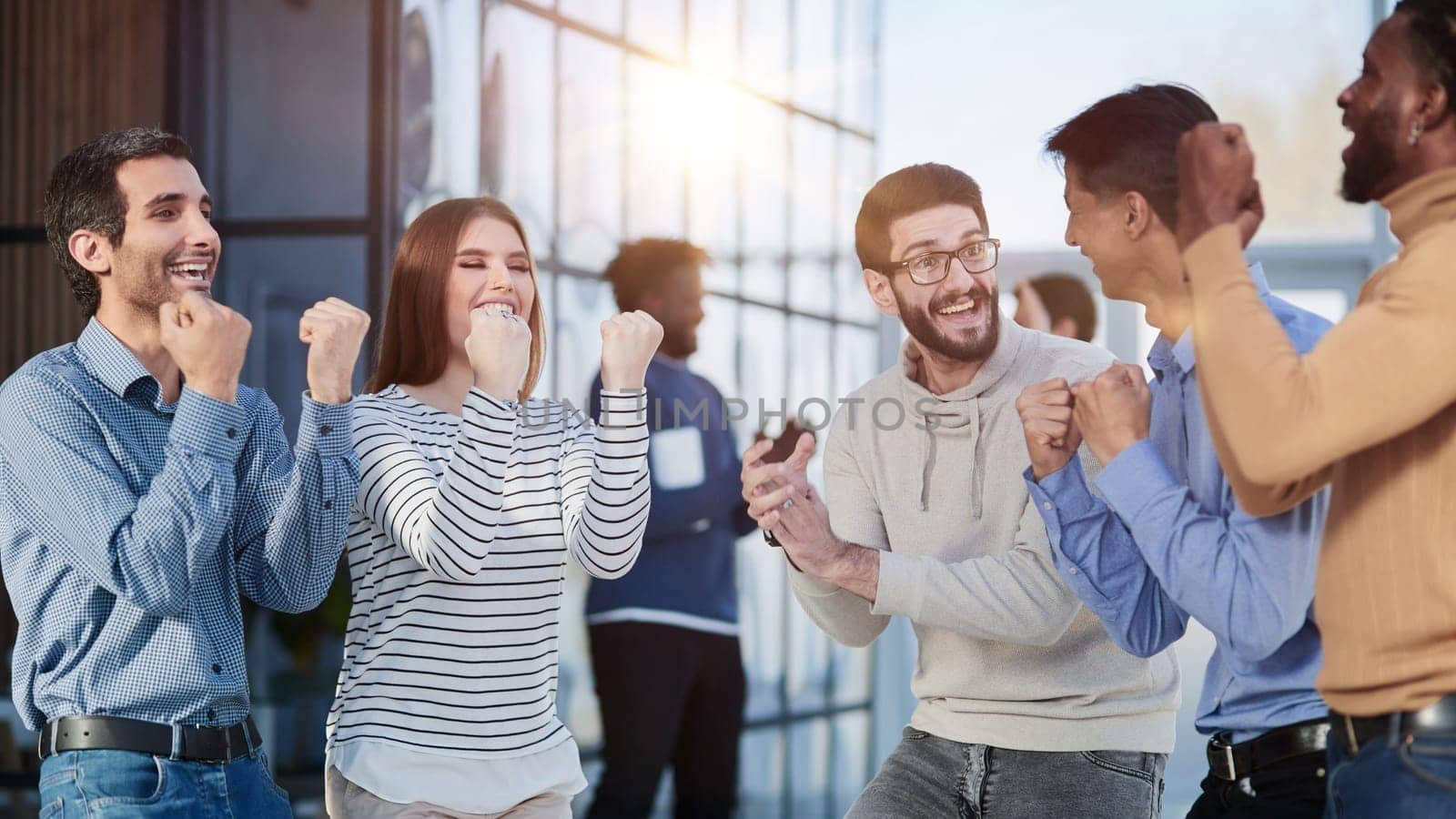 Group of happy managers rejoice at a successful deal by clenching their hands into fists and raising them up