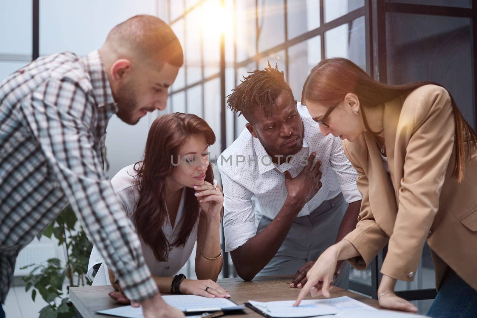 Group of young business people working together while standing in creative office