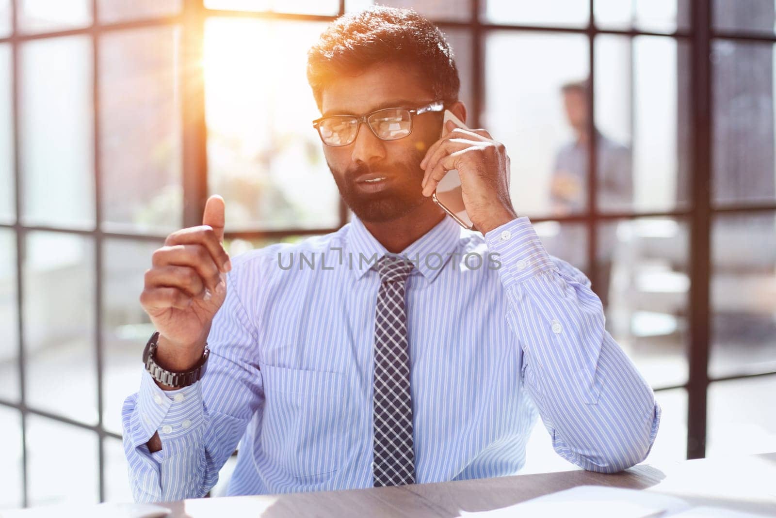 businessman sitting on chair at desk and talking on the phone
