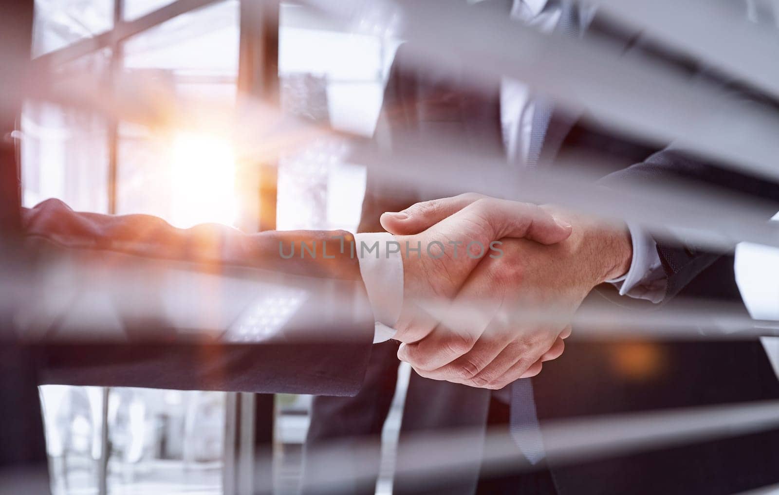 Two business people shaking hands in front of their colleagues