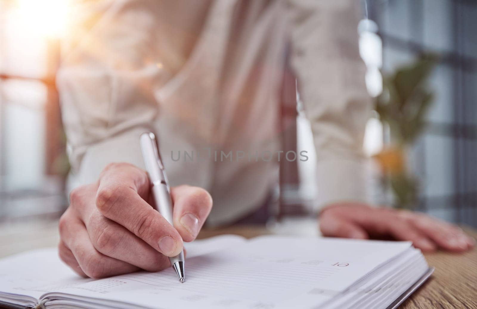 Businessman writes with a pen in diary sunny office, business and education concept.