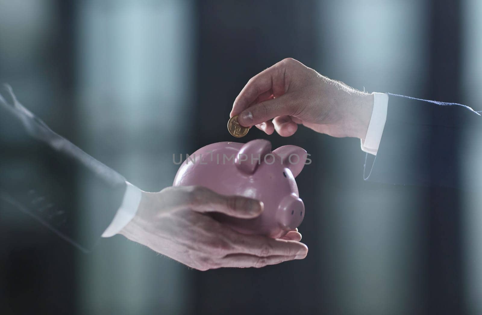 Hand puts a coin in a piggy bank on a black background by Prosto