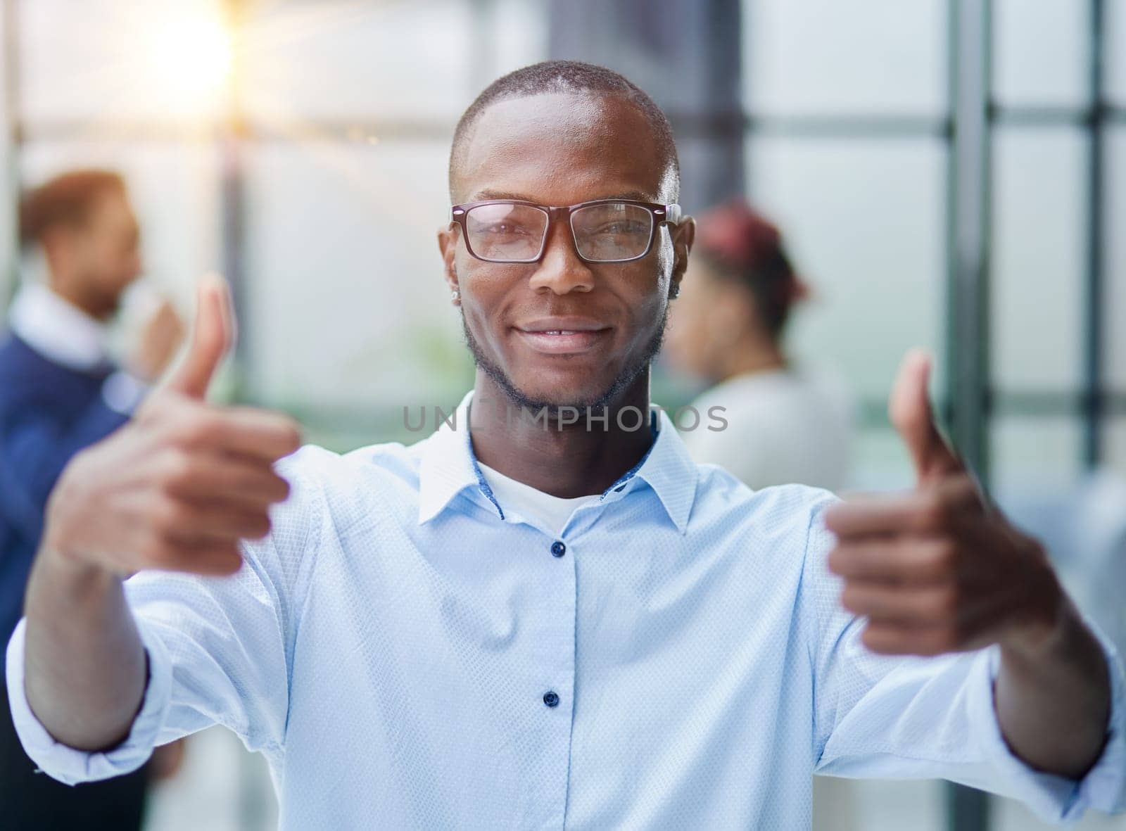 Businessman in glasses showing thumb up while looking at camera by Prosto
