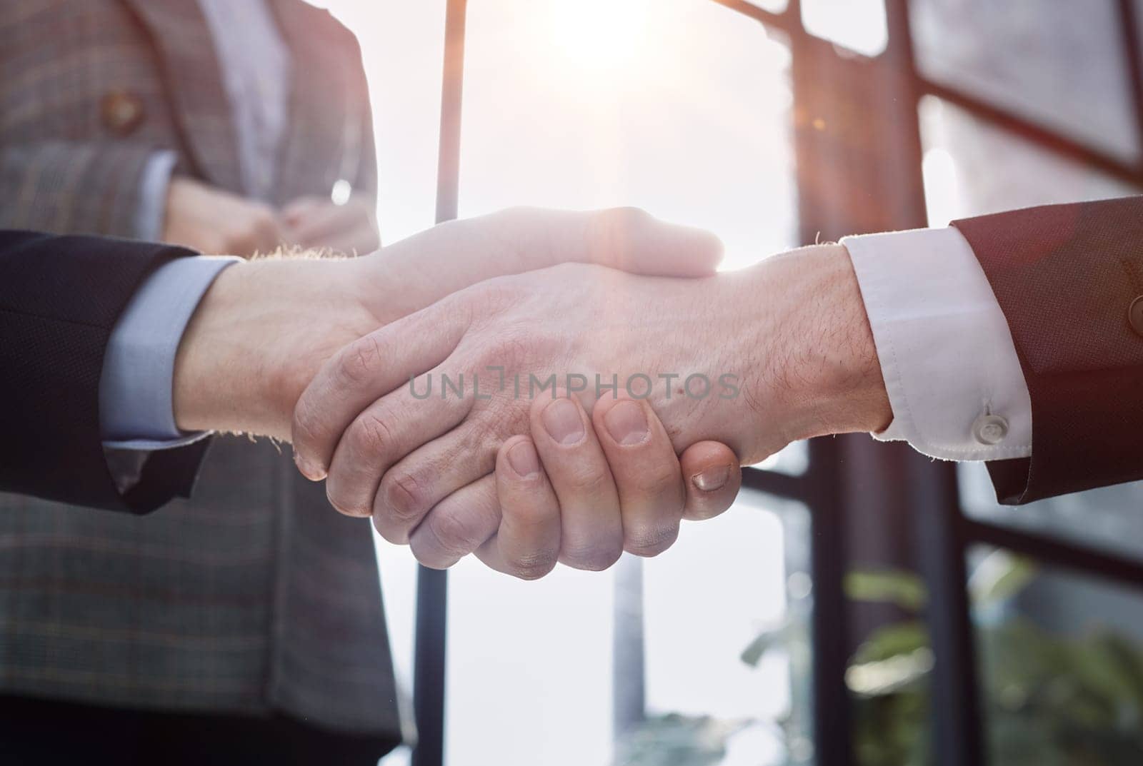 businessman shaking hands partnership deal business while standing indoors in the office by Prosto