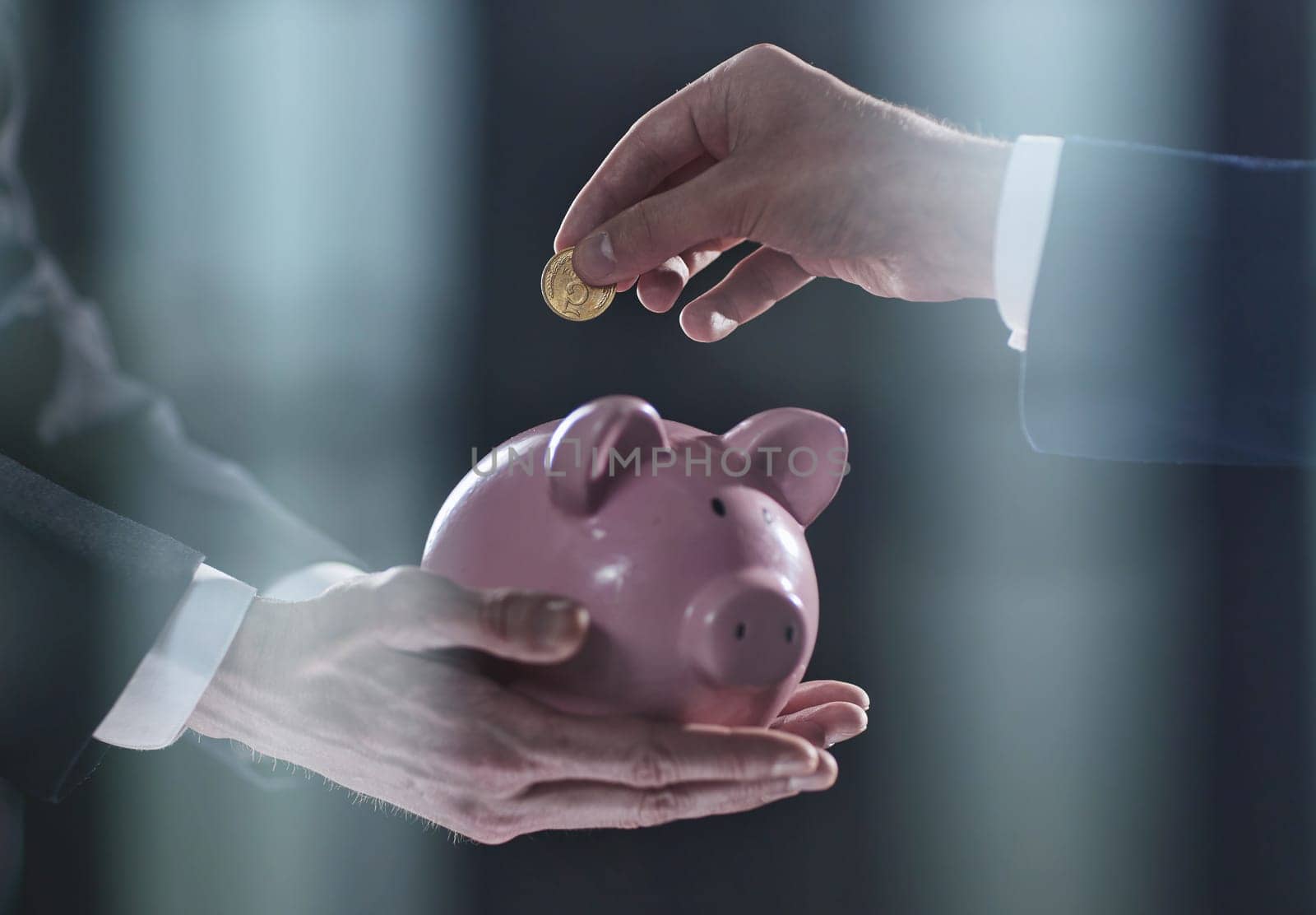 Hand puts a coin in a piggy bank on a black background. accumulation concept