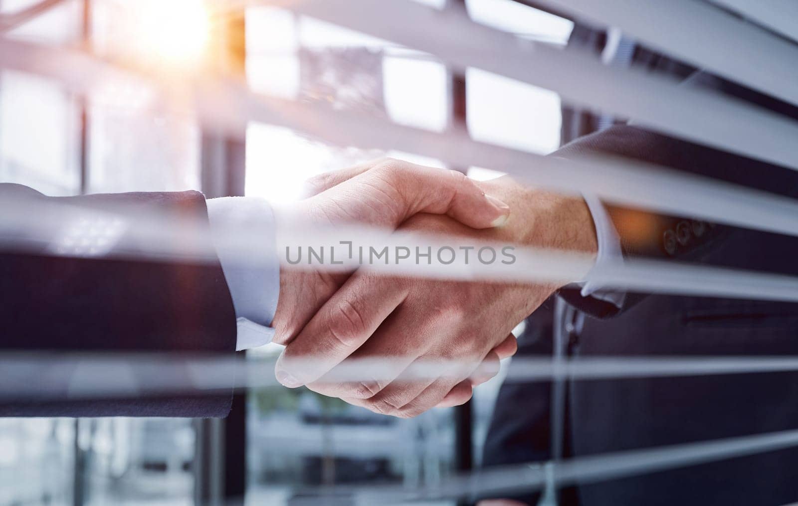 Two business people shaking hands in front of their colleagues