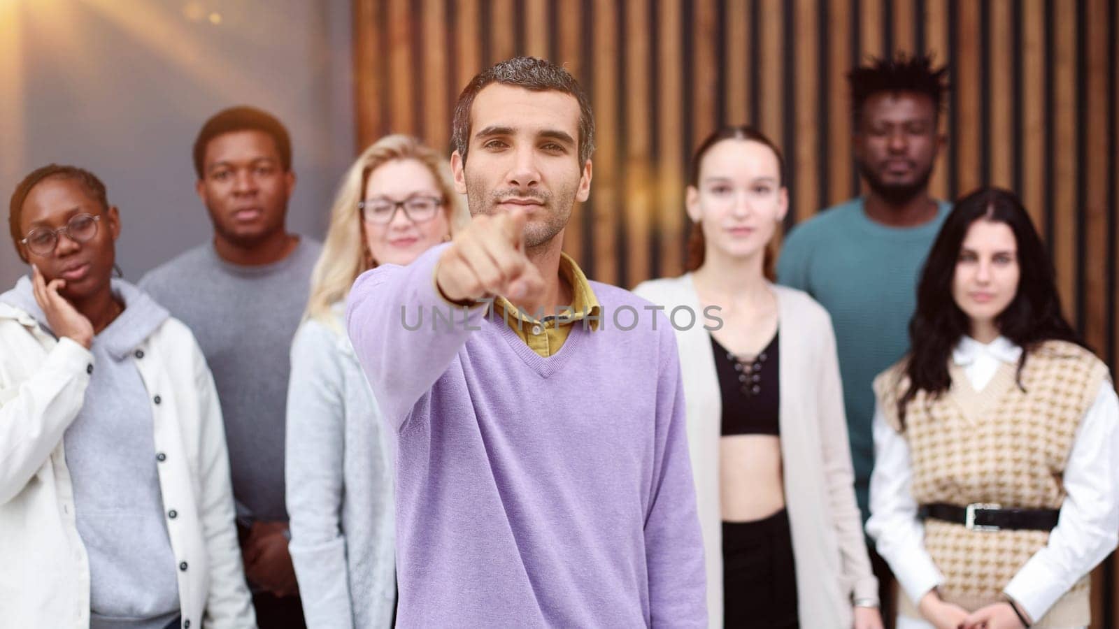 a man points at you against the background of colleagues in a modern office