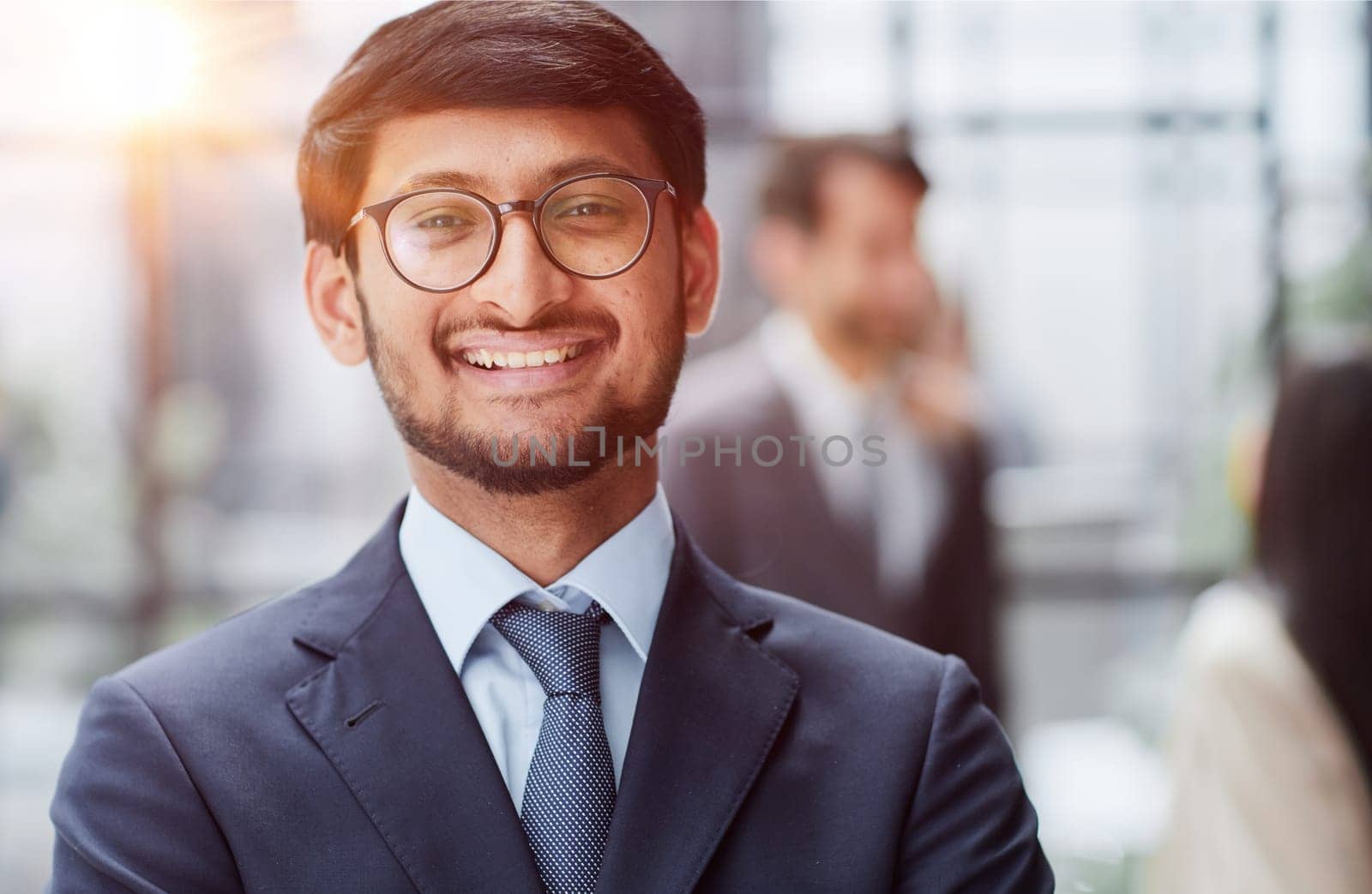 Handsome young business man in glasses standing confidently in the office