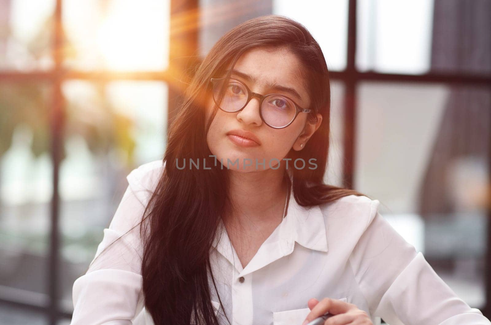 Photo of beautiful woman looking at camera while sitting at office