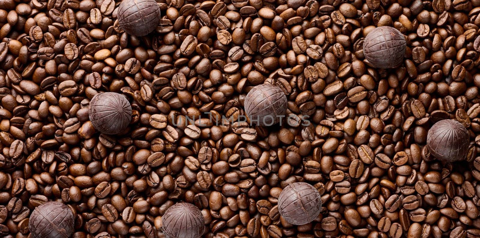 Scattered roasted coffee beans and round chocolate candies by ndanko